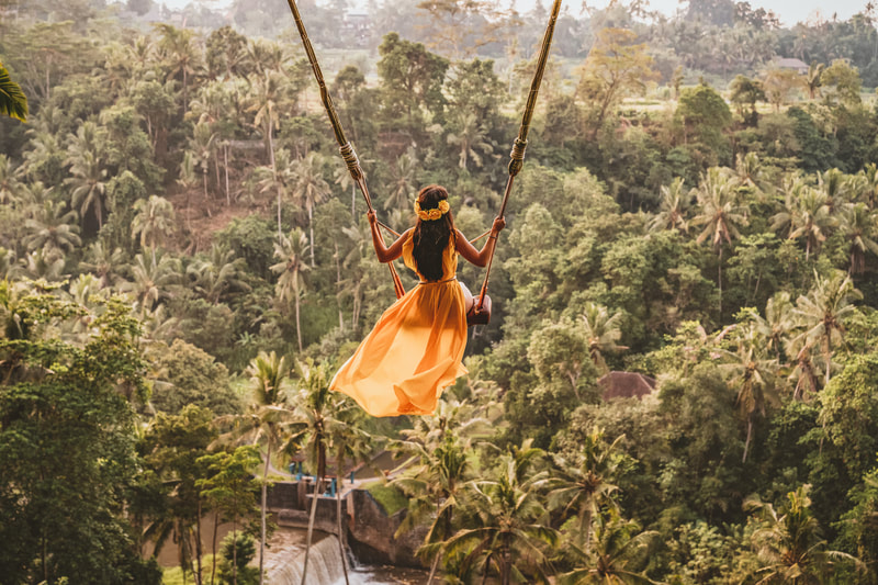 Woman soaring over Bali jungle in huge swing